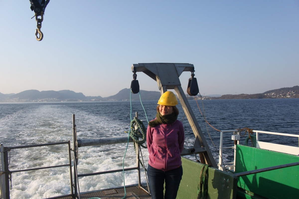 woman standing onboard a research vessel with a calm sea in the background
