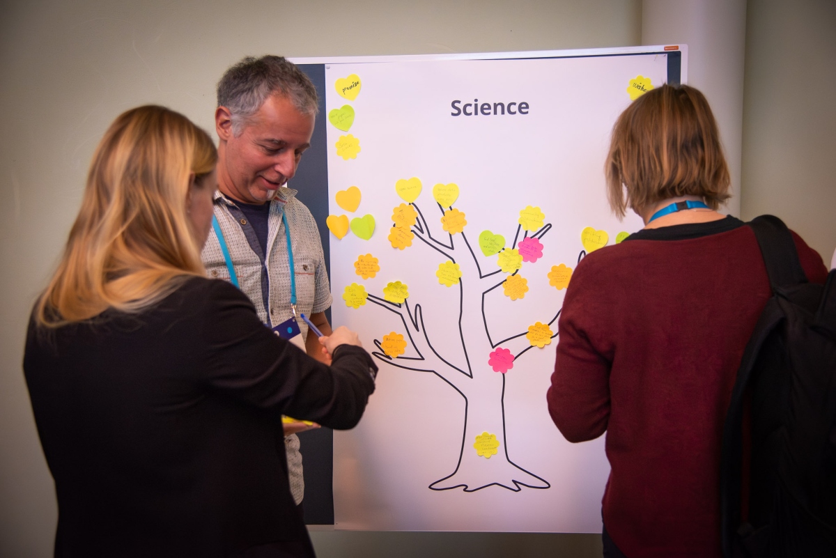 Three people around a poster with post-its 