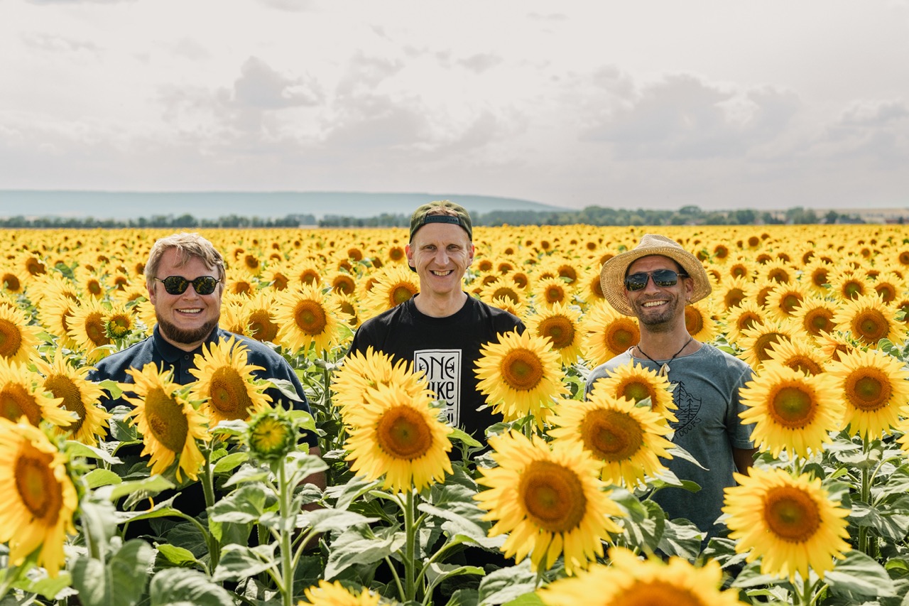 the crew of the Gebesee station smiling at the camera in the middle of sunflower field
