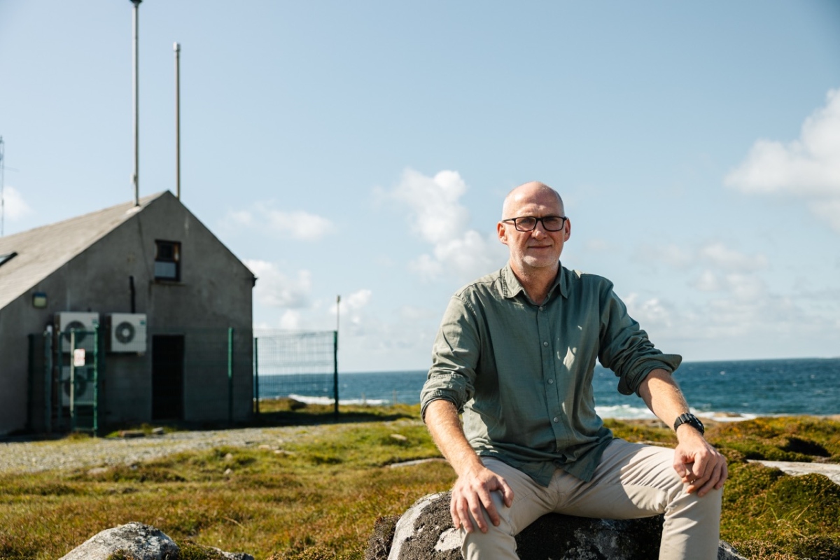 scientist smiling and looking at the camera with the station building on the background