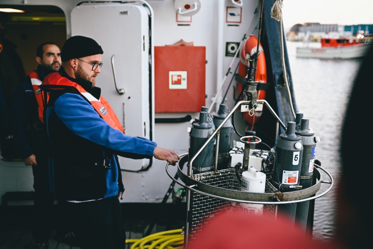 man getting ready to lower an instrument to water onboard a ship
