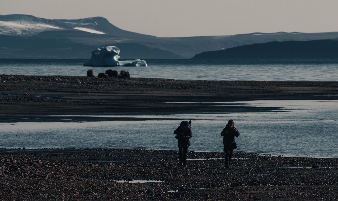 two scientists walking with backpacks on their backs in Greenland