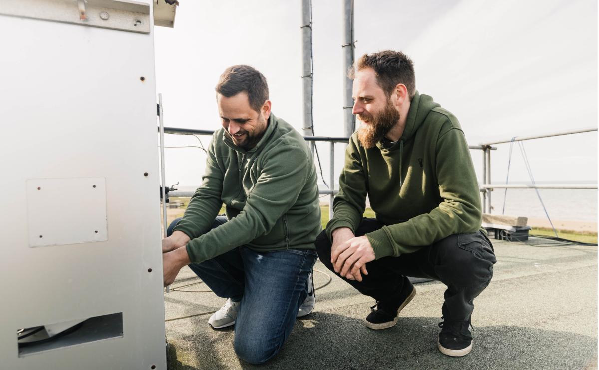 station PI and technician working on an instrument on the roof of the station