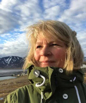 Ingunn Skjelvan looking to the left with a blue sky and mountains in the background