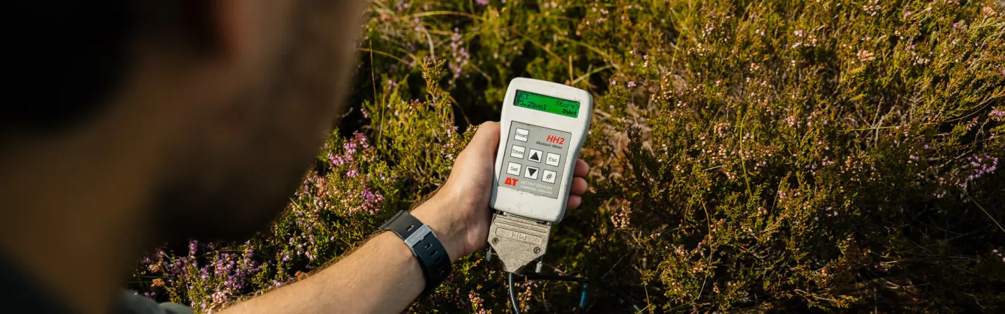 person holding a measurement device on a wetland site 