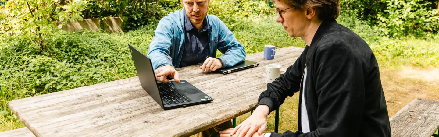 Two researchers reviewing data on a laptop outdoors.