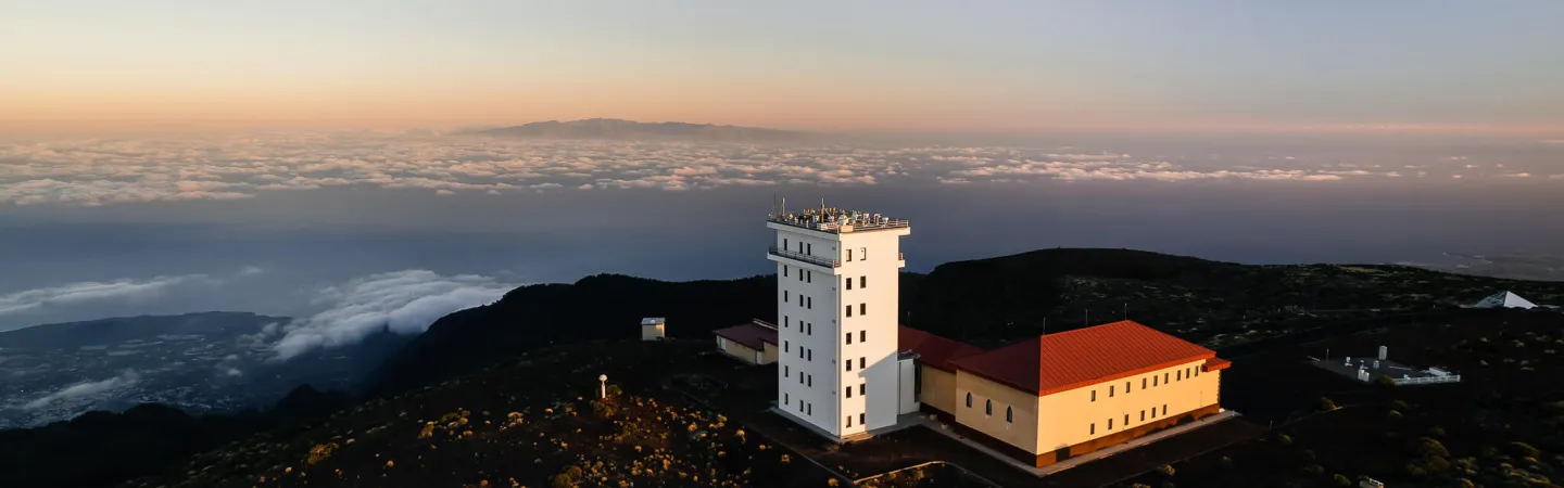 Mountain observatory building above a sea of clouds at sunset