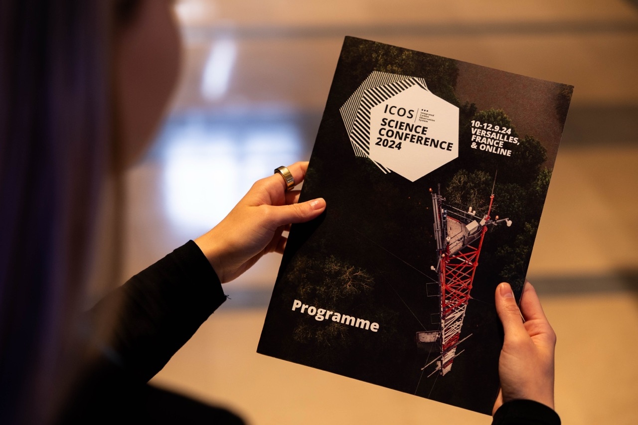 person holding a printed brochure of ICOS Science Conference