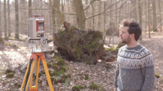 PhD student Miro DeMol standing next to a terrestial laser scanner