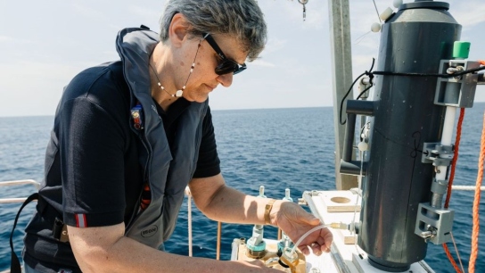 A scientist using an instument at sea.