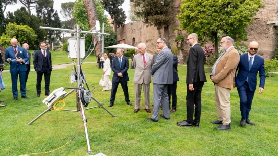 group of people standing around an eddycovariance instrument on green grass 