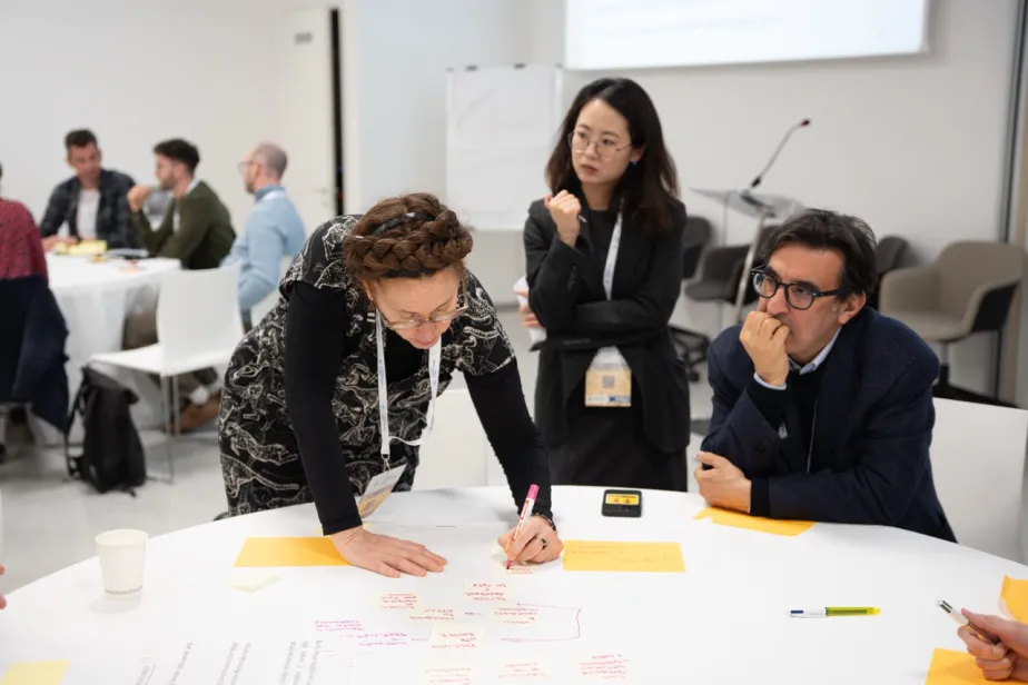 three people around a table writing on colourful post it notes 