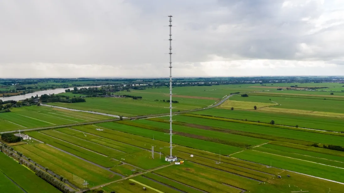 drone image of an atmospheric tower in the middle of green fields with a grey sky in the background