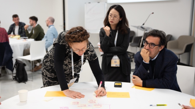 three people around a table writing on colourful post it notes 